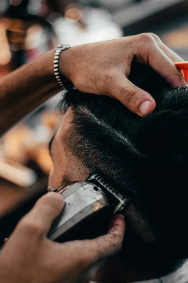 Mesin cukur merapikan sisi rambut seorang pelanggan