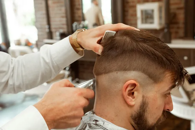 Mesin cukur membuat mid fade pada pelanggan berjenggot